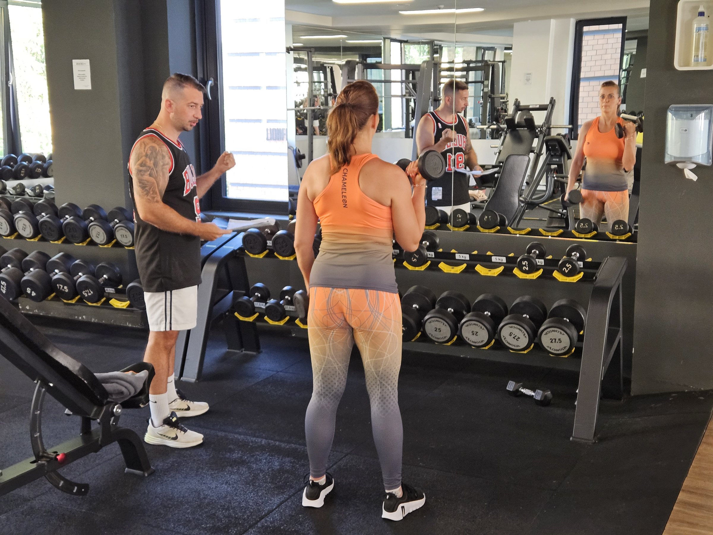 Dávid súlyzós gyakorlat közben segíti vendégét a Lion Fitnessben